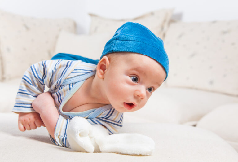 Cute 2 months old baby boy at home trying to roll over