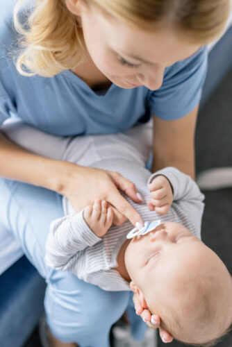 woman holding pacifier in babys mouth