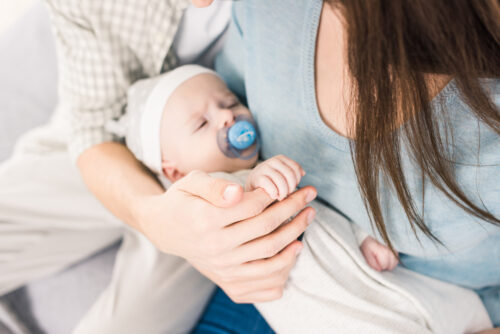 parents holding infant with pacifier