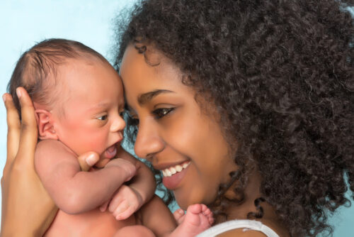 Mom holding newborn baby and smiling