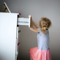 little girl climbing on dresser and nearly tipping it over