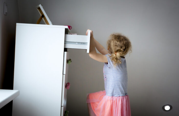 little girl climbing on dresser and nearly tipping it over
