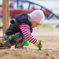 toddler playing with toy outside at a playground