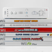 A studio shot of a stack of 6 Nintendo Wii video games and controller.