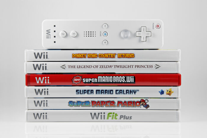 A studio shot of a stack of 6 Nintendo Wii video games and controller.