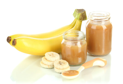 Baby food puree in jars with bananas isolated on white