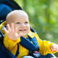 baby boy sitting in stroller during walk through park