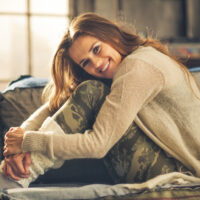 Smiling woman relaxing in leggings on sofa