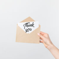 closeup of a woman's hand holding a thank you card