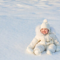 baby bundled up outside sitting in the snow