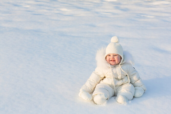 baby bundled up outside sitting in the snow