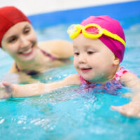 woman helping teach a baby to swim