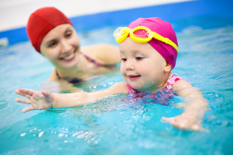 woman helping teach a baby to swim