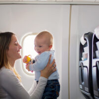 mom playing with baby while traveling on airplane