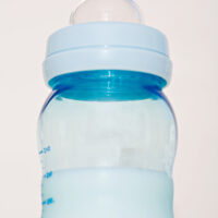 closeup of a blue baby bottle full of warm formula for baby