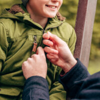 father zipping up his son's jacket