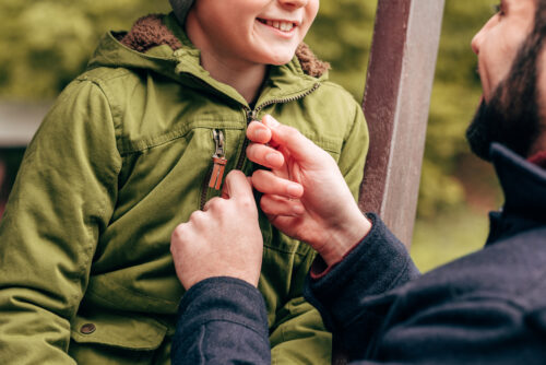 father zipping up his son's jacket