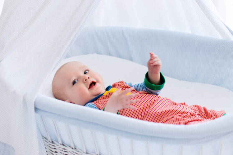 baby laying in a white bassinet