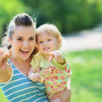 Happy mother and baby pointing in camera