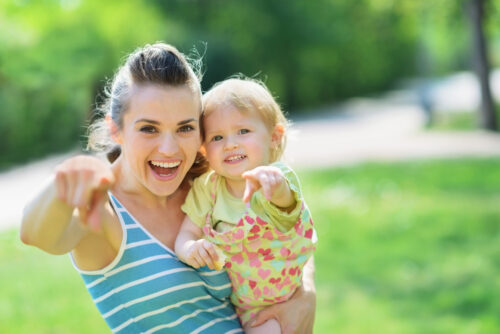 Happy mother and baby pointing in camera