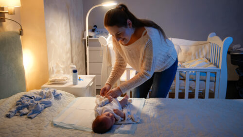 mother changing her baby's diaper at night
