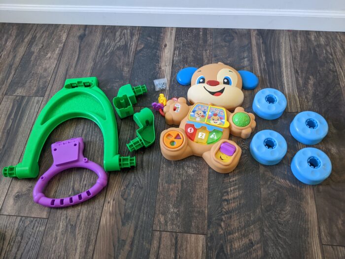 Fisher-Price Laugh & Learn Puppy Walker laying on the ground, out of the box, in 9 parts.