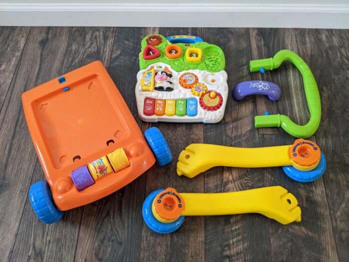 VTech Sit-to-Stand Walker out of the box laying on the ground in 6 parts.